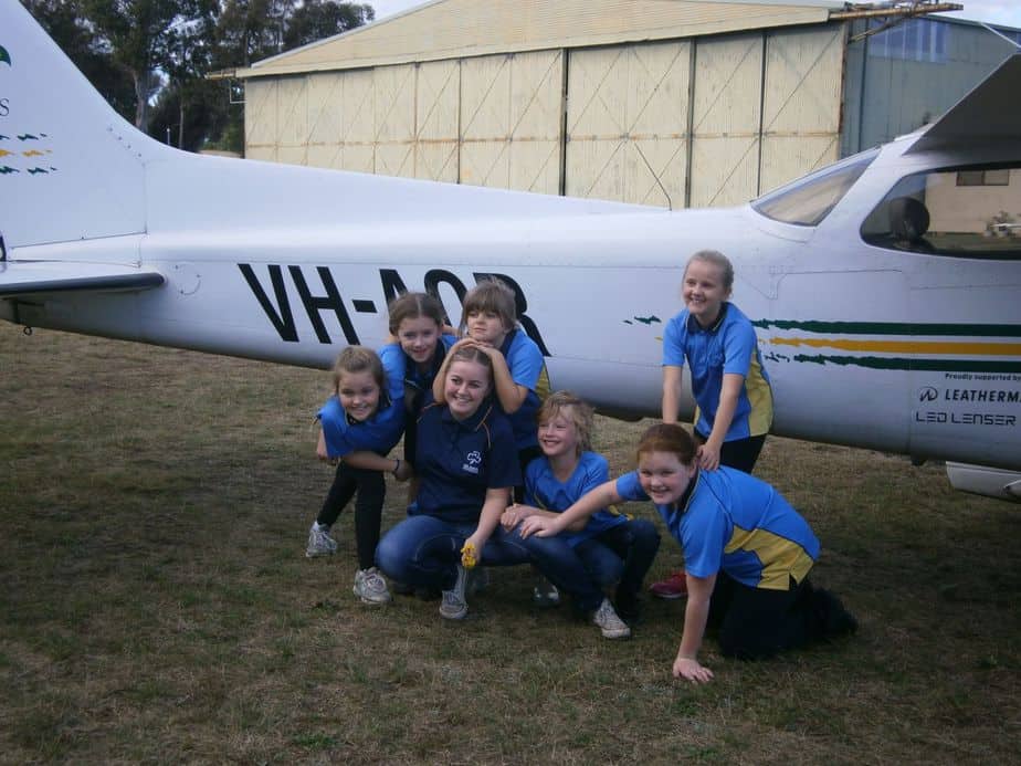 Group of Girl Guides posing in front of a plane